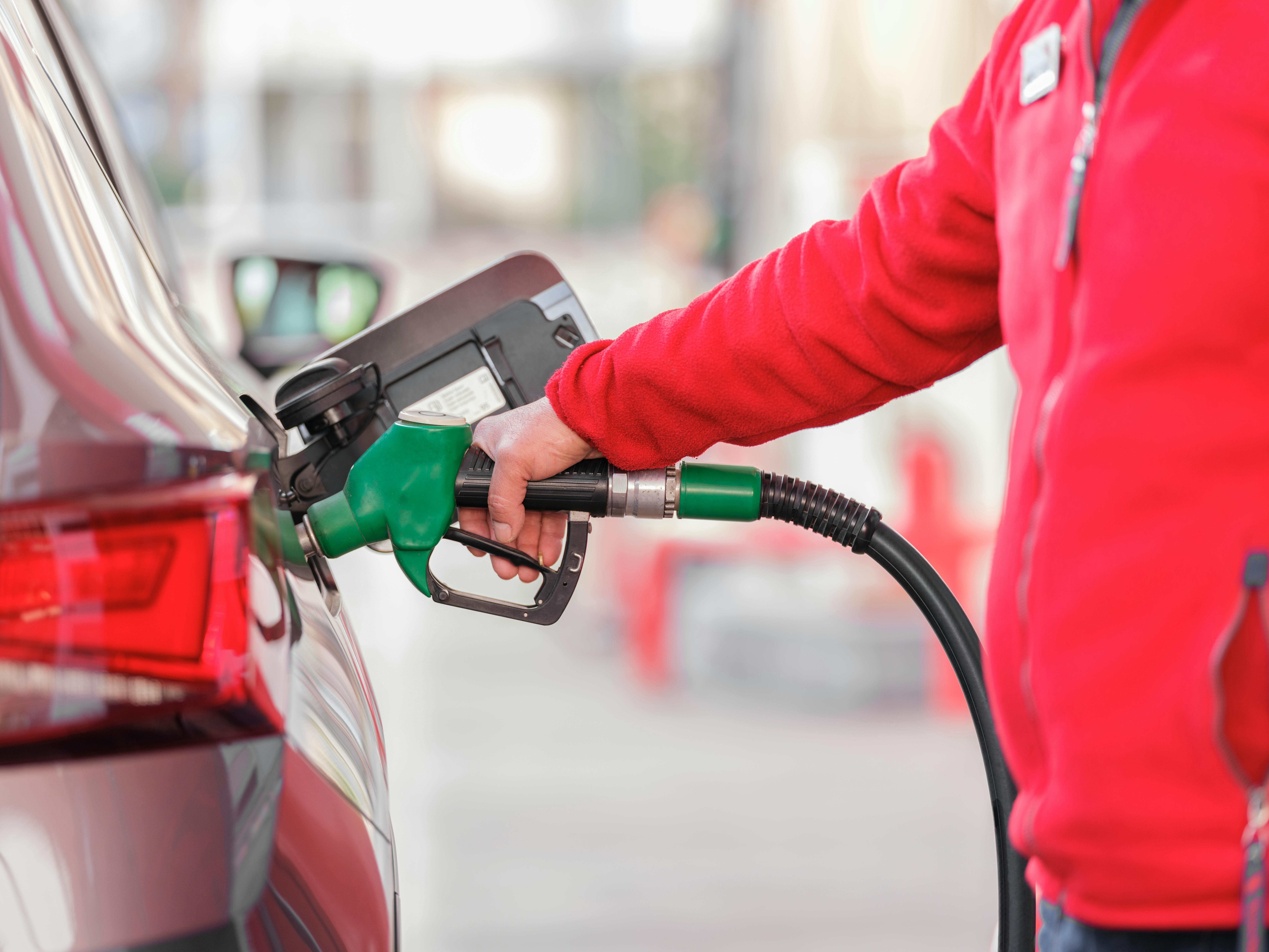 Ein Mitarbeiter tankt ein Auto an einer Tankstelle. Diese Szene verdeutlicht die Bedeutung der Automobilindustrie in Deutschland und den möglichen Einfluss der grünen Klimapolitik auf Arbeitsplätze in diesem Sektor.